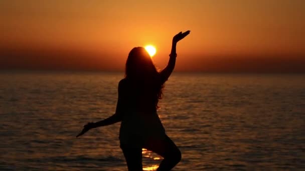 Медитация девушки на море во время заката. Силуэт йоги — стоковое видео