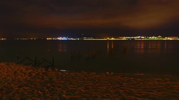 Timelapse de cidade noturna e mar com ondas pequenas . — Vídeo de Stock