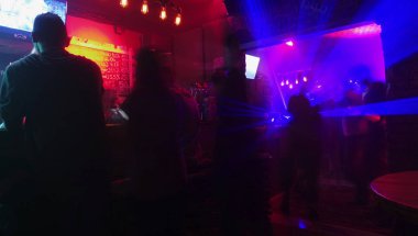 Modern gece kulüpte insanlar renkli ışık ile aydınlatılmış.