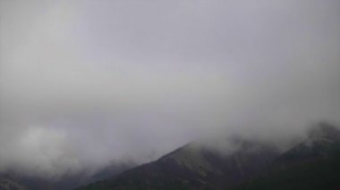 Timelapse. Bulutlar çevreleyen beyaz dağlar