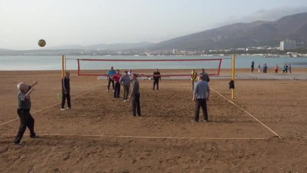 Пенсионеры играют в волейбол на пляже — стоковое видео