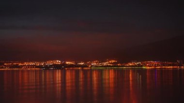 Timelapse. Gece şehir ve deniz üzerinde güzel bir akşam gökyüzü.