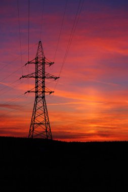 Renkli, ateşli, kırmızı gün batımı ve güneş pili etkisi. Gün batımında elektrik kablolarının ve kabloların görüntüsü