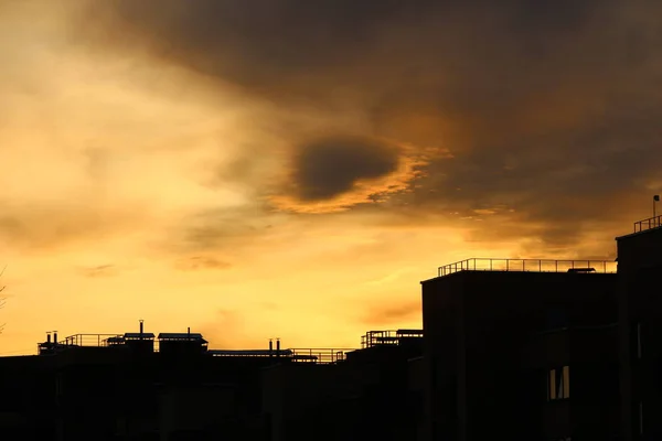 夕日の美しい雲の背景に新しい建物の暗いシルエット — ストック写真