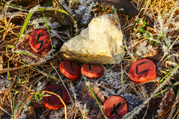 Carved wood runes and quartz druse on hoarfrost grass