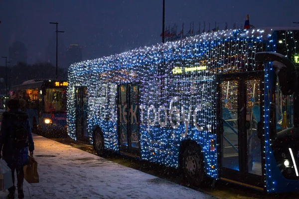 Moskova, Rusya - Ocak 2020: Moskova sokaklarında akşam saatlerinde yeni yıl çelenkleriyle süslenmiş bir elektrikli otobüs (elektrobus)