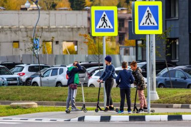 Rusya - Ekim 2019: Kick scooter kullanan bir grup çocuk otoyolun üzerinden yaya geçidinde. medyan adası
