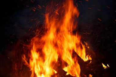 Renkli alevler ve karanlık bir arka plandaki şenlik ateşinden kıvılcımlar