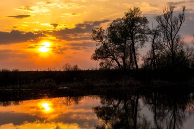 Suyun üstündeki bulutların ardında renkli bir günbatımı