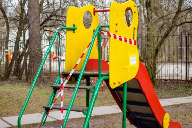 Çocuk kaydırağı, COVID-19 Coronavirus 'un yayılması nedeniyle çocuk parkındaki koruyucu bant ile sarılmış. Nisan 2020, Rusya