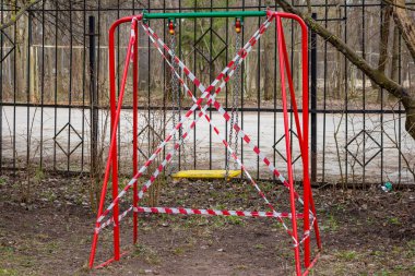 Salıncak, COVID-19 Coronavirus 'un yayılması nedeniyle oyun alanında koruyucu bir bant ile sarılmış. Nisan 2020, Rusya