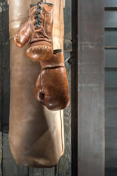 Klassische Braune Boxhandschuhe Mit Boxsack Und Holzhintergrund — Stockfoto