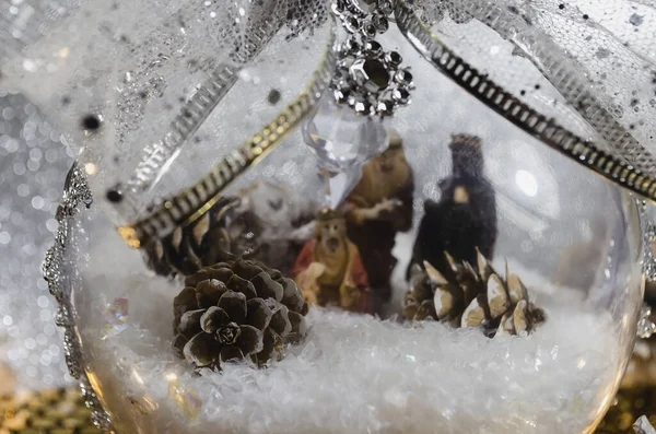 Bolas de Navidad transparentes llenas de nieve y con el nacimiento de Jesús y arcos dorados y luces cálidas — Foto de Stock