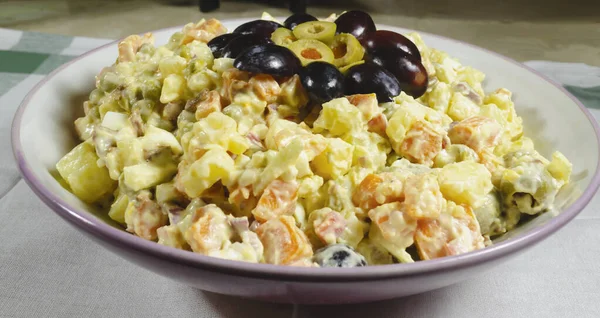 Russian salad dish typical Christmas dish, decorated with grapes cut in and green olives — Stock Photo, Image