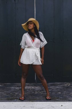 25-30 yaşları arasında siyah bir kadın, kilise kapısının önünde, beyaz mankenler giymiş, yeni yaz ve tropikal kıyafetler giymiş..