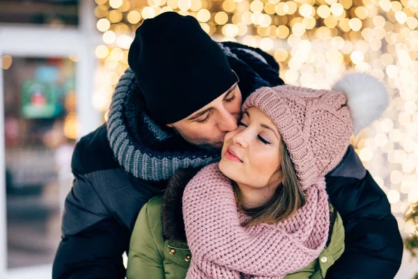 Young loving couple at the street with christmas lights on background