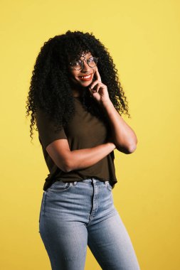 Sarı arka planda kıvırcık saçlı genç Afro-Amerikan kadın.