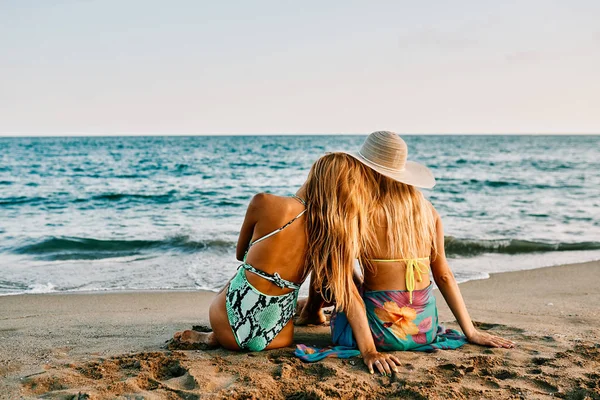 Twee jonge vrouwen aan het strand bij zonsondergang - zomerconcept — Stockfoto