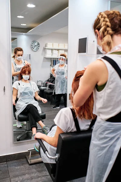 Frisör i skönhetssalong med ansiktsmask för att skydda mot coronavirus epidemi - social distansering koncept — Stockfoto