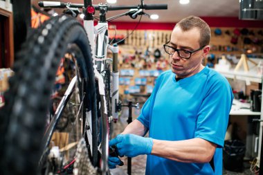 Bir adam küçük işletme atölyesinde bisiklet tamir eder.