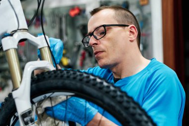 Bir adam küçük işletme atölyesinde bisiklet tamir eder.