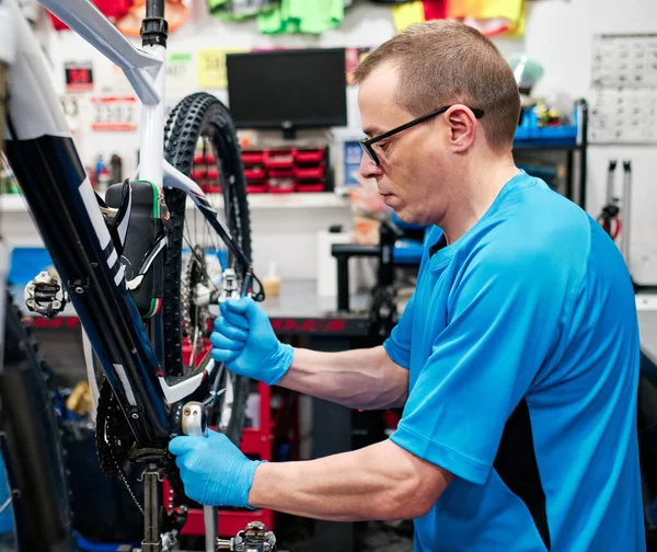 Bir adam küçük işletme atölyesinde bisiklet tamir eder.