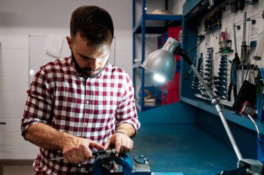 İtalyan atölyesinde çalışan orta yaşlı bir adam gitar ve enstrümanlarla gitar çalıyor.