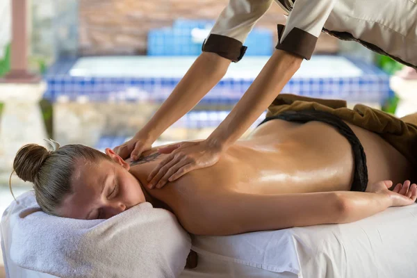 Mujer joven recibiendo masaje de piedra caliente en el salón de spa. Belleza tratar — Foto de Stock