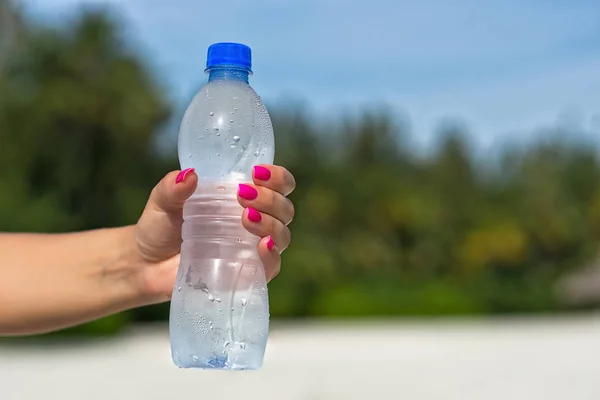 Kobieta rękę trzymając butelkę wody na zewnątrz — Zdjęcie stockowe