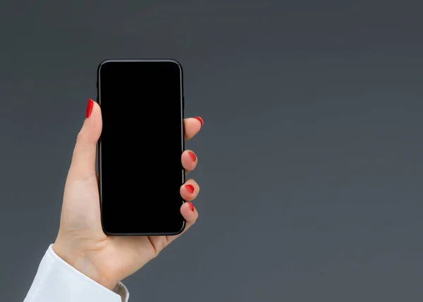 Ruční přidržovaní mobilního telefonu na šedém pozadí — Stock fotografie