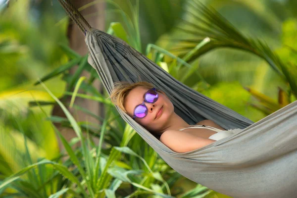 Young beautiful woman relaxing in hammock in a tropical resort. — Stock Photo, Image