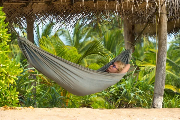 Young beautiful woman relaxing in hammock in a tropical resort. — Stock Photo, Image