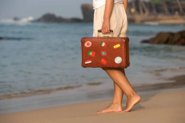 Bella ragazza con una vecchia valigia vintage in una spiaggia — Foto Stock