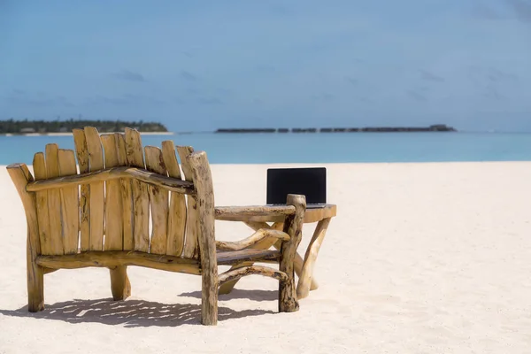 Pantalla en blanco portátil en escritorio de madera con playa. relajar concepto . —  Fotos de Stock