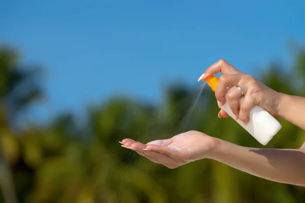 Mujer manos poniendo protector solar de una botella de crema solar —  Fotos de Stock