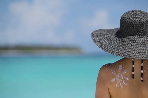 Mujer con crema solar en forma de sol en la playa —  Fotos de Stock