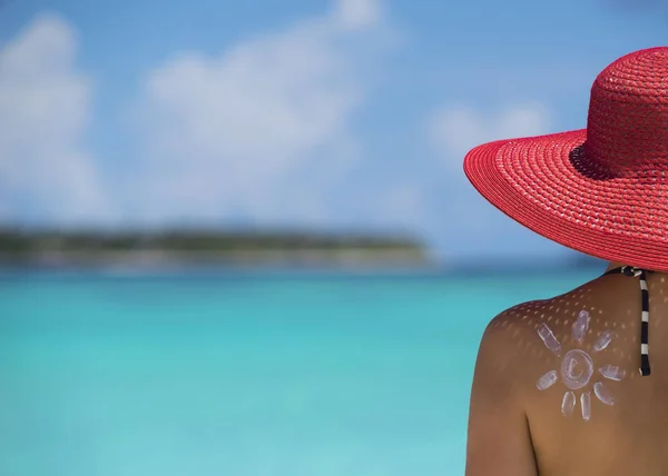 Femme avec crème solaire en forme de soleil sur la plage — Photo