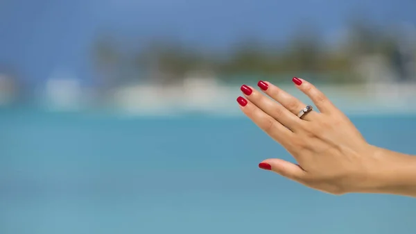 Close up of woman finger showing engagement ring on the tropical
