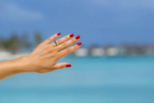 Zavřít ženský prst ukazující zásnubní prsten na tropickém — Stock fotografie