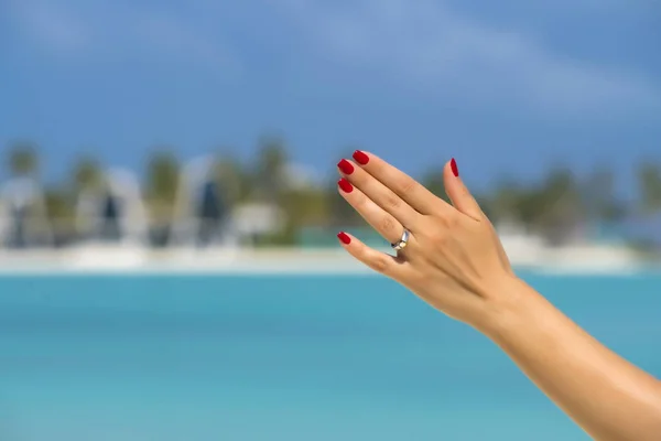 Primer plano del dedo de la mujer que muestra el anillo de compromiso en el tropical —  Fotos de Stock