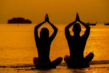 Fitness, sport and outdoor yoga concept - silhouettes of couple 