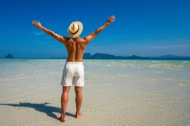 Sexy man with muscular torso enjoy sunny day on Thailand beach. Man sunbathing and relax on beach. Summer beach vacation for muscular man.