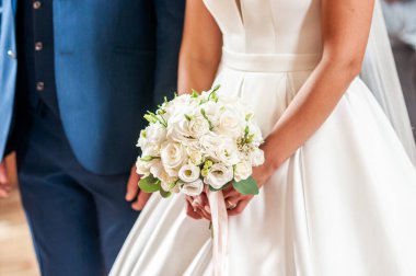 Damat ve gelin çiçek buketi üzerinde el ele tutuşuyor