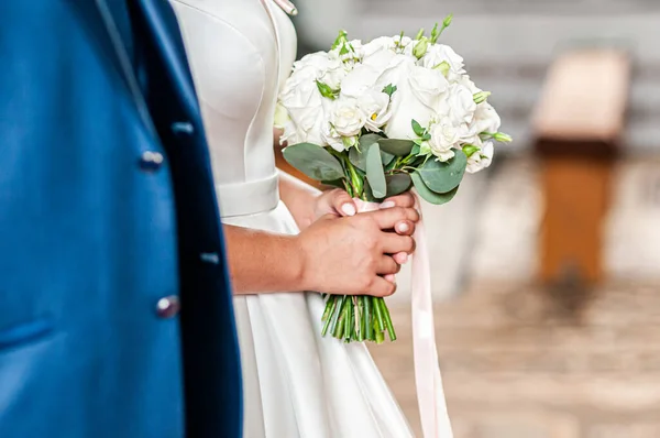 Жених и невеста держатся за руки на букете цветов — стоковое фото