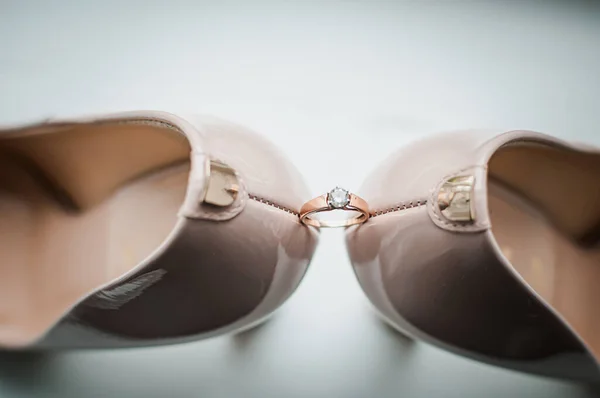 白い靴のペアの間の金色の結婚指輪のペア — ストック写真