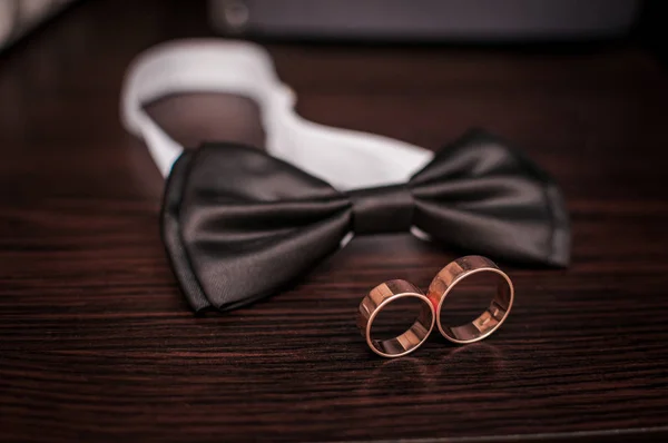 Par de anéis de casamento de ouro e gravata no pescoço na mesa — Fotografia de Stock