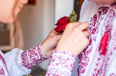 Kız, damat yaka çiçeğini gömleğine geçirir.