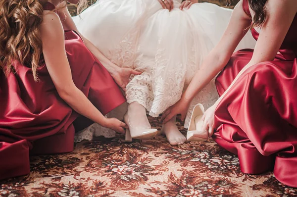 Damas de honor ayudando a la novia a ponerse zapatos elegantes —  Fotos de Stock