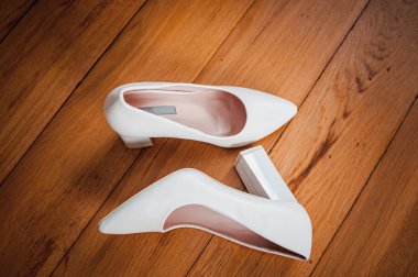 Beyaz topuklu kadın ayakkabıları ve yerde beyaz düğün jartiyeri.