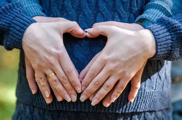 La mujer embarazada y el hombre se toman de la mano en forma de corazón —  Fotos de Stock